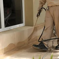 General pest control technician spraying exterior perimeter around a home in Bloomington, IN